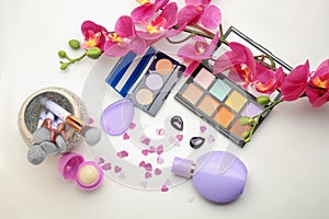 Composition with decorative cosmetics, brushes and orchid flowers on white background