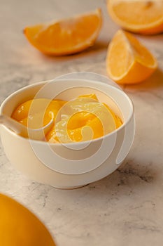 Composition with delicious Yellow lemons and Lemon curd in a sausepan white bowl on marble background