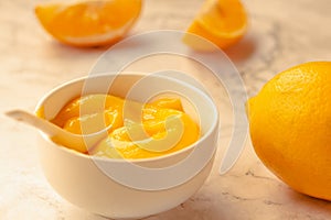 Composition with delicious Yellow lemons and Lemon curd in a sausepan white bowl on marble background