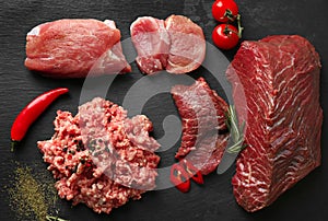 Composition with different sorts of fresh meat on dark background