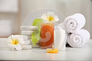 Composition with different spa products and plumeria flowers on white marble table