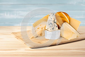 Composition of different types of cheese on wooden background. blue cheese Dorblu, smoked Suluguni, brie, Maasdam, cheddar,
