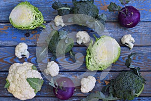 Composition from different varieties of cabbage on wooden background. Cauliflower, kohlrabi, broccoli, white head cabbage. Organic