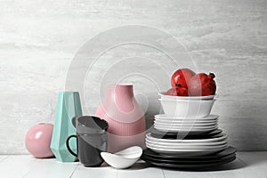 Composition with dinnerware and vases on table against light background.