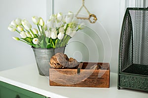 Composition of dried artichoke flowers in wooden box and a bouquet of white tulips in a vase as home decoration. Modern style flow