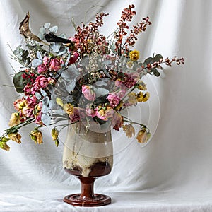 composition of dry flowers in a vase, white fabric background, still life