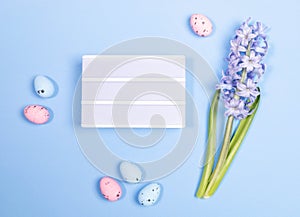 Composition of Easter decorations. Color eggs, hyacinth on blue. Space for inscription. Top view.