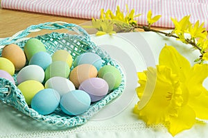 Composition for Easter holidays:  basket with colored chocolate eggs, on the right of spring flowers