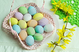 Composition for Easter holidays: pink basket with colored chocolate eggs, on the right of spring flowers