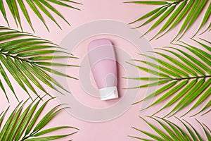 Composition with empty travel cosmetics bottle palm leaf on pink background Top View