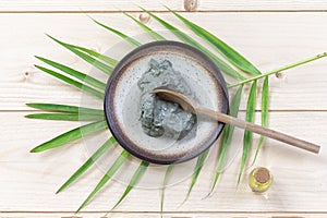 Composition of essential oil and clay for facial mask and nody care, in cup wellness concept on green plam leaf, slate