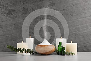 Composition with essential oils diffuser on table against grey background