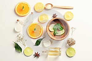 Composition with essential oils and sliced fruits on white background, top view