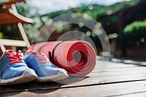 Exercise mat and trainers outdoors on a terrace in summer.