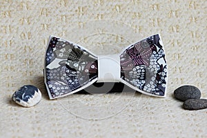 Composition: Extravagant bow tie and pebbles on a beige background.