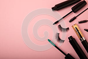 Composition with false eyelashes, mascara and eyelash brushes, eyelash curlers on background.