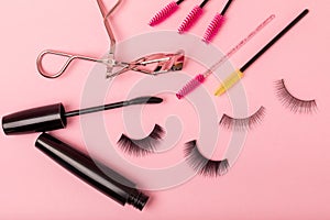 Composition with false eyelashes, mascara and eyelash brushes, eyelash curlers on background.