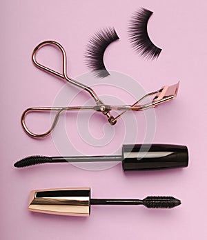 Composition with false eyelashes, mascara and eyelash brushes, eyelash curlers on background.