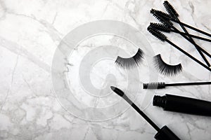 Composition with false eyelashes, mascara and eyelash brushes, eyelash curlers on background.