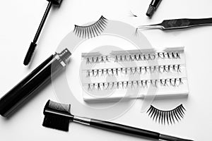 Composition with false eyelashes and tools on white background