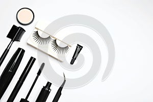 Composition with false  and other makeup products on white background, top view