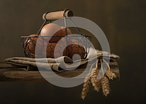 Composition with farm products. Basket of eggs, bunch of wheat ears.