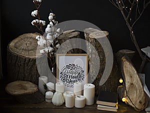 Composition from fellings of trees against a dark background, standing on a wooden floor together with candles and an inscription photo