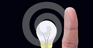 Composition of finger touching lit light bulb on grey background