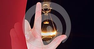 Composition of finger touching screen with lightbulb on black background