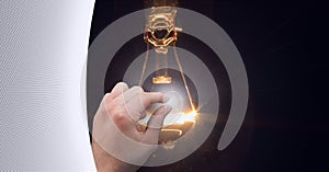 Composition of finger touching screen with lightbulb on black background