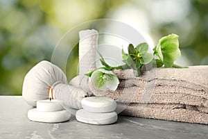 Composition with flowers and spa supplies on marble table against blurred green background