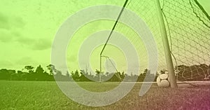 Composition of football on white line by goal post on grass pitch with copy space and green tint