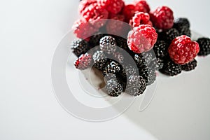 The composition of fragrant and delicious black and red raspberries on a white background are isolated in the studio