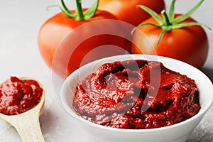 Composition of fresh cherry tomatoes, tomato sauce in a gravy boat on a marble background.