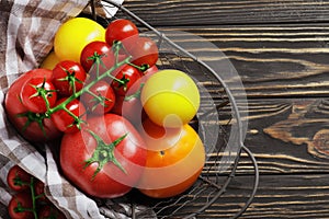 Composition of fresh ripe tomatoes of different varieties, spices, basil, rosemary, thyme, hot pepper in a basket on a wooden boar