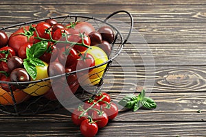 Composition of fresh ripe tomatoes of different varieties, spices, basil, rosemary, thyme, hot pepper in a basket on a wooden boar