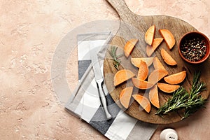 Composition of fresh sweet sliced potatoes, rosemary spice, pepper, salt, knife, sliced kitchen towel on a wooden background