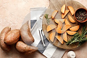 Composition of fresh sweet sliced potatoes, rosemary spice, pepper, salt, knife, sliced kitchen towel on a wooden background