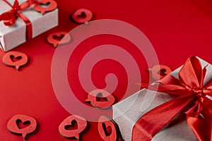 composition with a gift box tied with a red ribbon with a bow, hearts close-up on a red background. Concept for