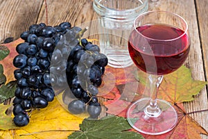 Composition with glass of red wine and grapes on wooden table close-up