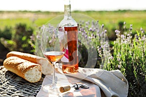 Composition with glass of wine on wicker table in field