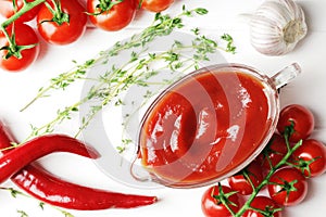 Composition of a gravy boat filled with delicious tomato sauce, a branch of fresh cherry tomatoes,