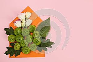 Composition of green chrysanthemums Santini and roses in an envelope on a pink background