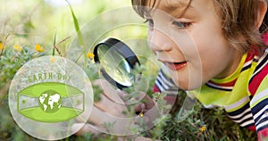 Composition of green globe logo and earth day text over boy using magnifying glass in nature