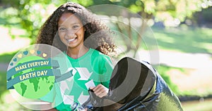 Composition of green globe logo and earth day text over smiling girl cleaning up the countryside