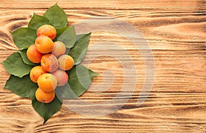 Composition with green leaves and ripe sweet apricots on wooden table