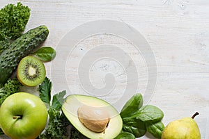 Composition with green vegetables and fruits on white wooden background