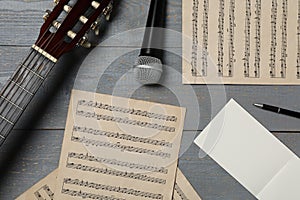 Composition with guitar and music notations on grey wooden table, flat lay