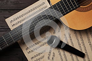 Composition with guitar and music notations on wooden table, flat lay