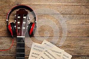 Composition with guitar and music notations on wooden table, flat lay. Space for text